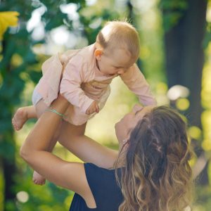 Fotografin Baby wird Überkopf gehalten und lacht dabei seine Mutter an